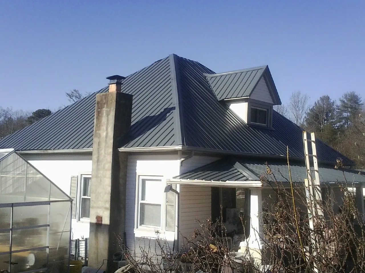 Dark blue standing seam metal roof on a white farmhouse with dormer — Slate & Tile Roof Repair by Roofing Brothers in South Bay