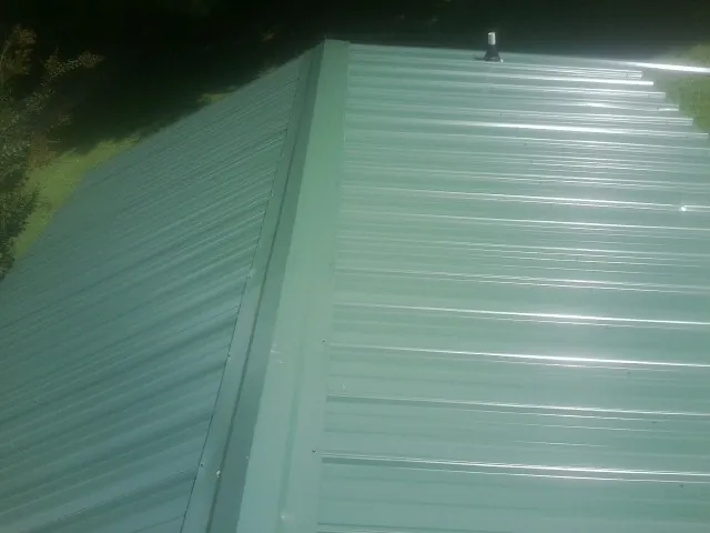 New green metal panels meeting at the ridge of a roof — Flat Roof Repair work by our crew in South Bay