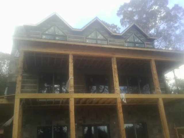 Dormers and porch framing on a large log home under construction — Roof Coating work by our crew in South Bay