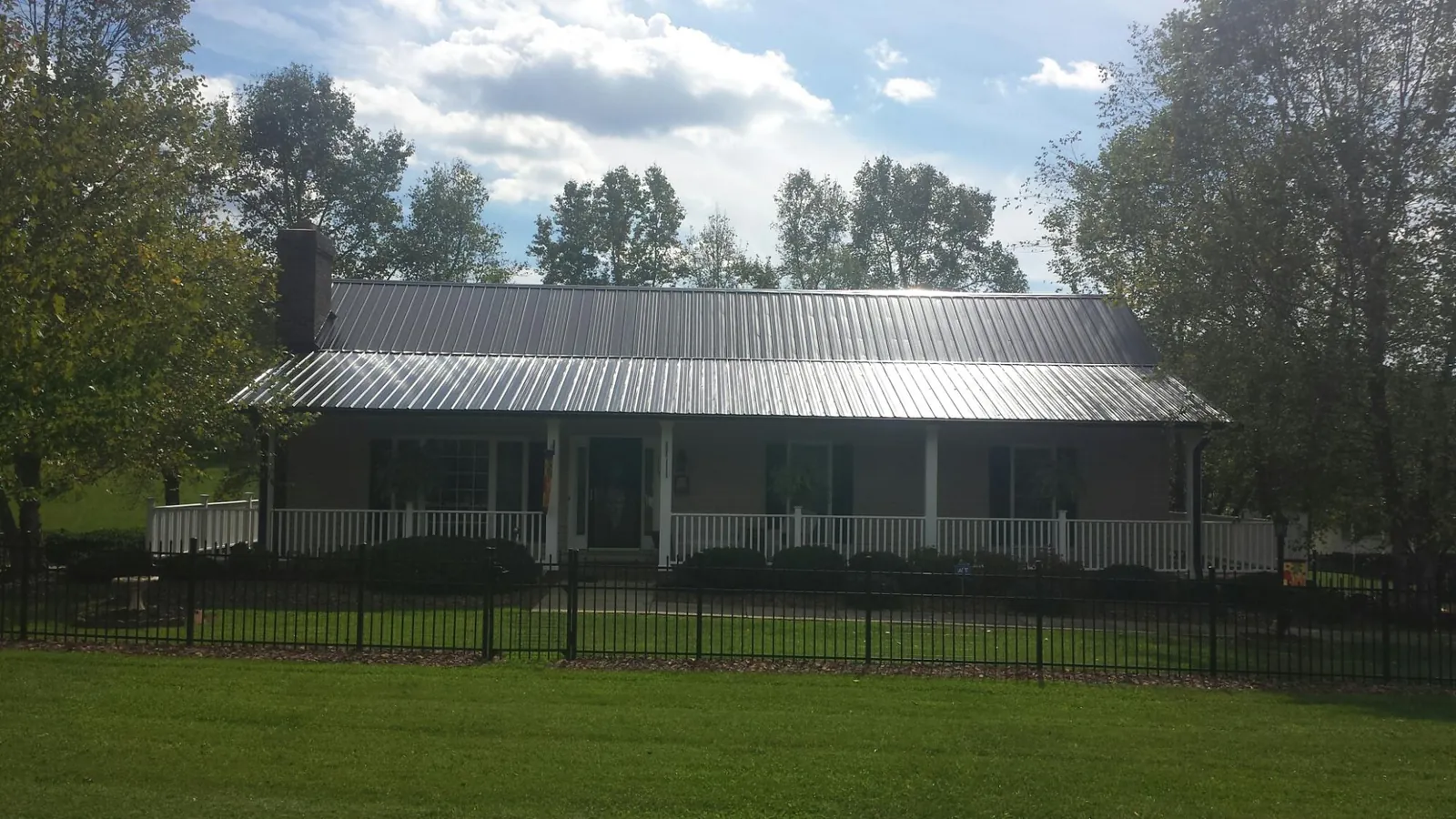 Gray metal roof on a brick ranch with a full width front porch — Gutter Guard Installation work by our crew in South Bay