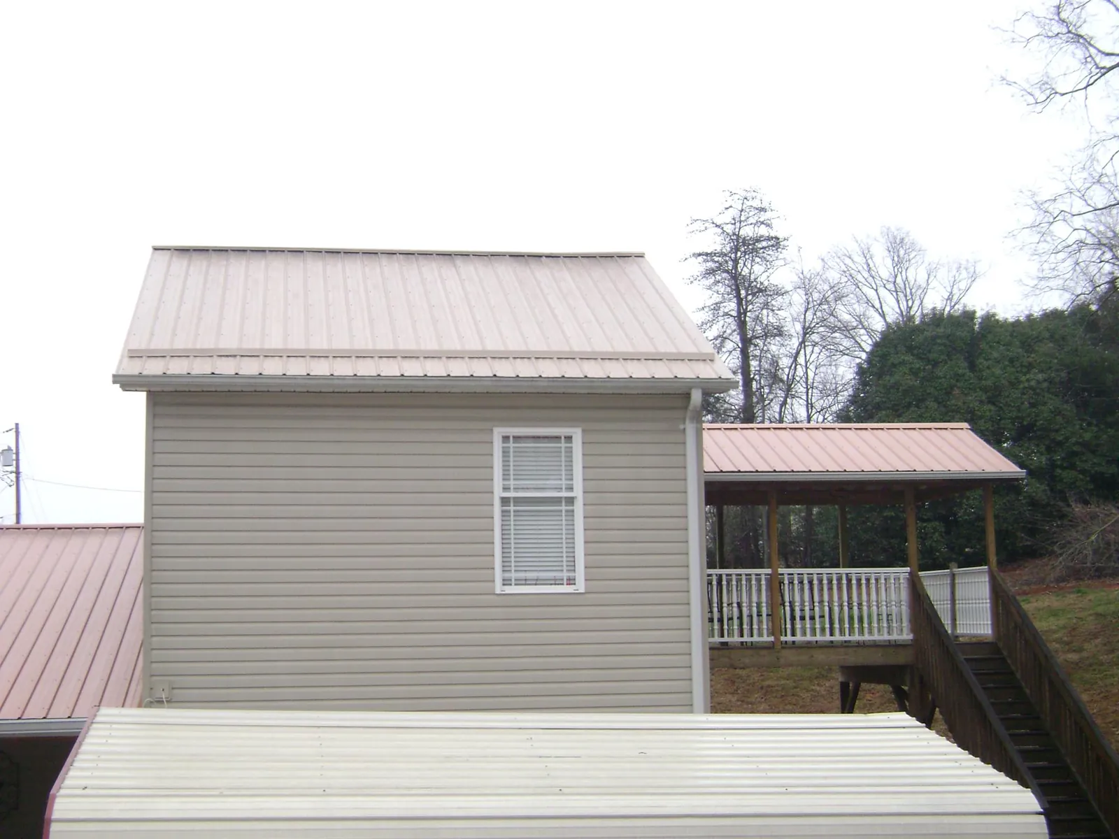 Tan metal roofs on a two story addition and attached porch, from a Roof Replacement job in South Bay