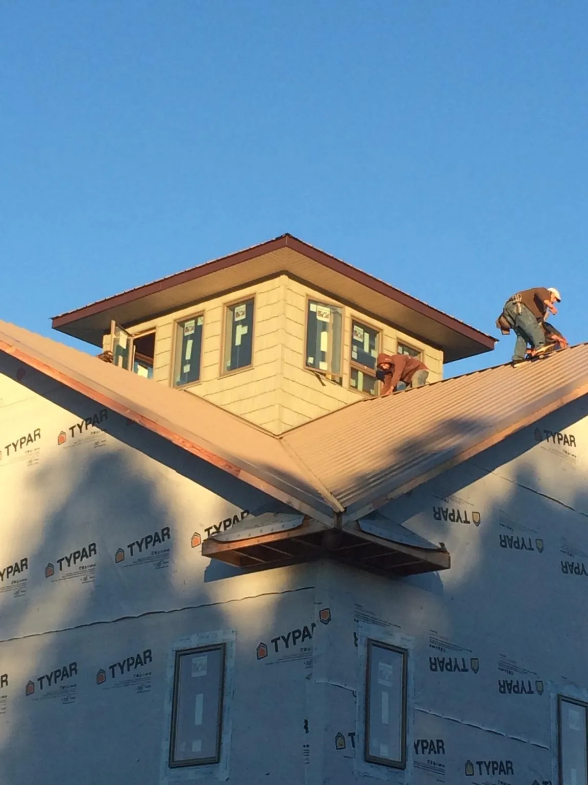 Roofers working around a rooftop cupola on a new metal roof at sunset — Roof Waterproofing in South Bay by Roofing Brothers